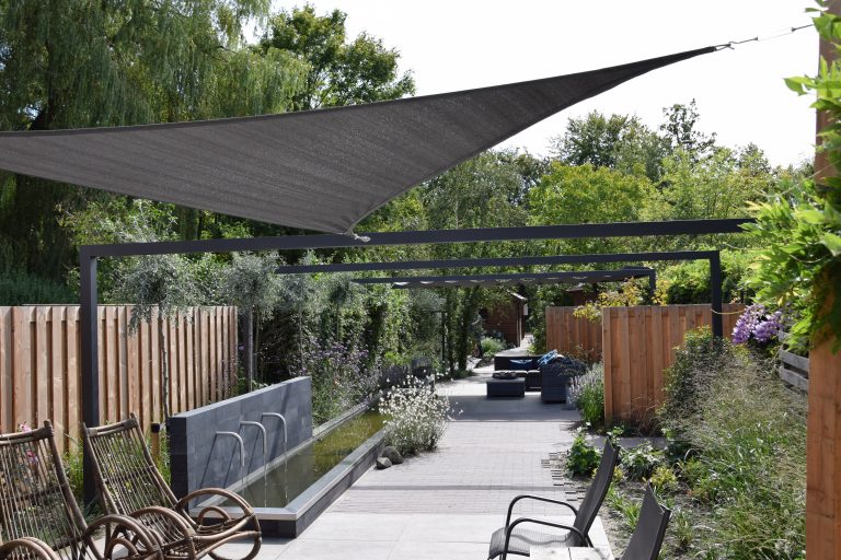 Hele lange smalle tuin met pergola's en schaduwdoek.