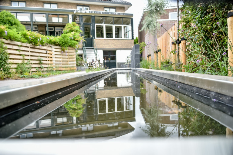 Lange moderne vijver in smalle tuin.