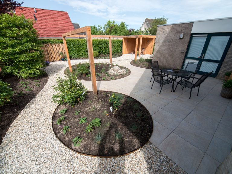 Strakke mediterrane tuin met ronde borders en pergola.