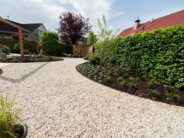 Tuin in mediterrane sfeer | kiezelstenen en pergola en ronde borders.