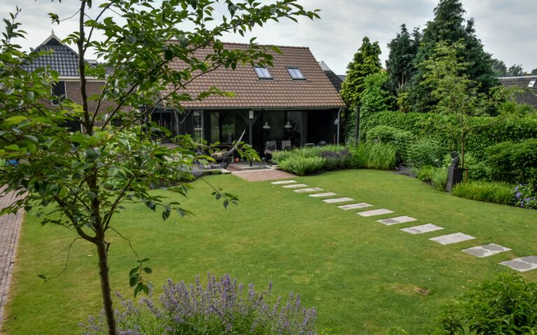 Landelijke strakke achtertuin met tuinhuis en paadje.