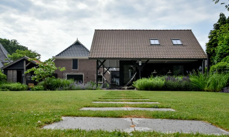 Landelijke strakke tuin met pad en tuinhuis.